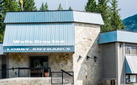 Der Eingangsbereich des Wells Gray Inn zeigt eine moderne Fassade mit Steinverkleidung und einem blauen Dach.