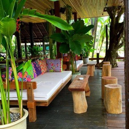 Gemütliche Lounge im Sepilok Nature Resort mit bunten Kissen und Holzbestuhlung umgeben von tropischen Pflanzen.