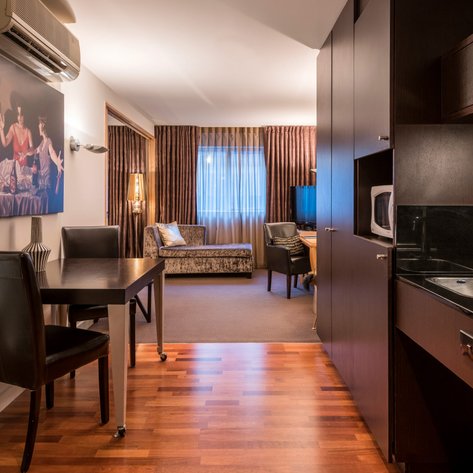 Ein elegantes Apartment mit einer modernen Küche, einem Esstisch und einem gemütlichen Wohnbereich im Hintergrund.