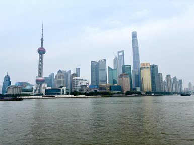 Die beeindruckende Skyline von Shanghai zeigt moderne Wolkenkratzer und den ikonischen Oriental Pearl Tower am Wasser.