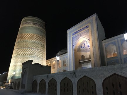 Die beleuchtete, kunstvoll verzierte Moschee und der hohe Minarettturm strahlen in der Dunkelheit eine majestätische Atmosphäre aus.