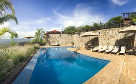 Ein einladender Poolbereich mit Liegen und Sonnenschirmen, umgeben von üppigem Grün und einer beeindruckenden Aussicht.