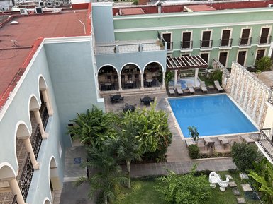 Ein ruhiger Innenhof mit einem Pool, umgeben von Palmen, Stühlen und einem Wasserbrunnen, ideal für Entspannung.