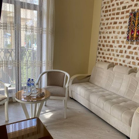 Ein elegantes Loungezimmer mit einem bequemen, hellen Sofa und zwei Stühlen, die um einen kleinen Tisch angeordnet sind.