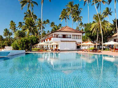Ein glitzernder Pool umgeben von Palmen und einem eleganten Resort, ideal für entspannende Tage in der Sonne.