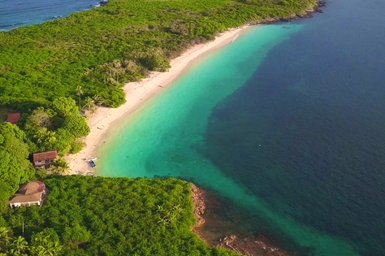 Eine atemberaubende Küstenlandschaft mit klarem, türkisfarbenem Wasser und einem ruhigen, sandigen Strand im Vordergrund.