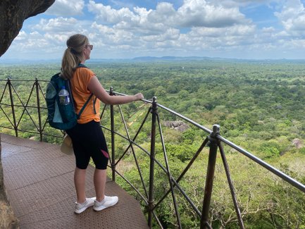 Frau blickt vom Sigiriya-Felsen auf die grüne Landschaft und den weiten Horizont – Sri Lanka Familienreise
