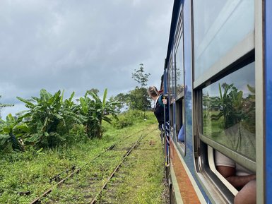Frau blickt aus dem Fenster eines blauen Zuges während der Fahrt – Sri Lanka mit Kindern