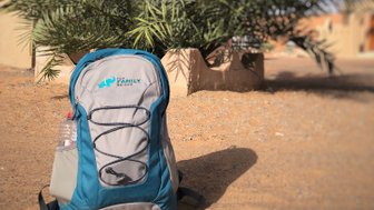 For Family Reisen Rucksack liegt auf Sand vor Palme im Oman – Oman mit Kindern