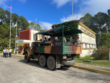 Ein geländegängiger Jeep steht vor dem Informationszentrum, während Touristen auf der Ladefläche sitzen und die Umgebung genießen.