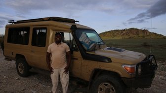 Safari-Guide neben Jeep am Abend – Tansania mit Kindern