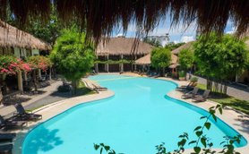 Ein einladender Pool mit klarem Wasser, umgeben von tropischen Pflanzen und gemütlichen Liegen in einem Resort.