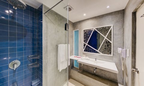 Ein modernes Badezimmer mit blauen Fliesen, einer eleganten Dusche und einem stilvollen Waschbecken, das einladend wirkt.