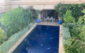 Ein klarer Pool glänzt in der Sonne, umgeben von üppigem Grün und komfortablen Gartenmöbeln für entspannende Stunden.