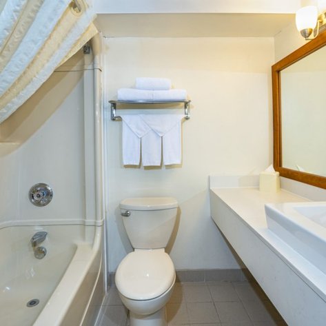 Ein modernes Badezimmer mit einer Badewanne, einem Waschbecken und einem großen Spiegel, der den Raum hell erscheinen lässt.