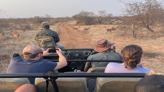 Familie unternimmt eine spannende Pirschfahrt mit Guide und beobachtet Antilopen in der Savanne – Südafrika Familienreise