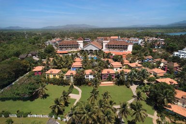 Eine Luftaufnahme des Radisson Blu Resorts in Goa, umgeben von üppigem Grün und bunten Gebäuden mit roten Dächern.