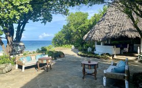 Ein einladender Außenbereich mit einem gemütlichen Sofa und einem Tisch, umgeben von üppigem Grün und Blick auf das Meer.
