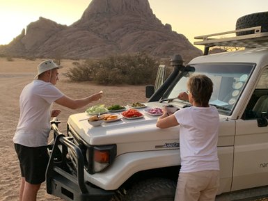 Eine Mutter isst mit ihrem Sohn auf der Motorhaube eines Jeeps - Namibia mit Jugendlichen