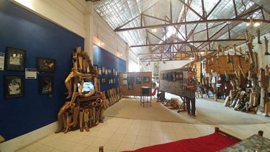 Ein Mann steht in einem Museum, umgeben von Ausstellungsstücken, die aus Holzprothesen bestehen und an Wänden hängen.