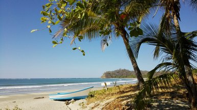 Boot liegt am Ufer neben Palmen am Strand von Sámara – Costa Rica Familienreise