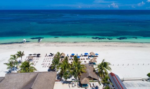 Ein atemberaubender Blick auf den weißen Sandstrand von Puerto Morelos, umgeben von Palmen und klarem, blauem Wasser.