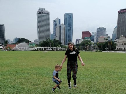 Mutter und Kind springen auf einer grünen Wiese in Kuala Lumpur – Malaysia & Borneo Familienreise