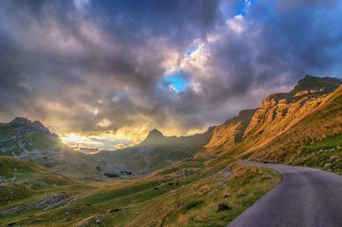 Eine kurvenreiche Straße schlängelt sich durch die atemberaubende Landschaft des Durmitor-Nationalparks, umgeben von majestätischen Bergen.