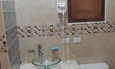 Ein modernes Badezimmer mit einer runden Glaswaschschüssel und einem eleganten Wasserhahn auf einer marmorierten Arbeitsplatte.