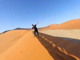 Ein Junge steht auf dem Kamm einer Sanddüne in der Wüste - Namibia Urlaub mit Kindern