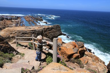 Baby schaut von oben auf das Meer in Mossel Bay entlang der Garden Route – Garden Route Familienreise