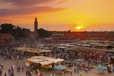 Djemaa el Fna Platz mit Menschen und Marktständen im Licht des Sonnenuntergangs in Marrakesch – Marokko Reise mit Kindern