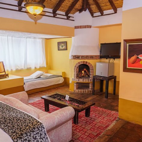 Ein gemütlicher Raum mit einem Kamin, einem Sofa und einem Tisch, umgeben von warmen Gelbtönen und einem rustikalen Ambiente.