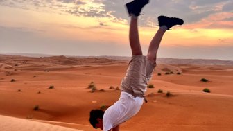 Junge macht Handstand in der Wahiba-Wüste beim Sonnenuntergang – Oman Reise mit Kindern