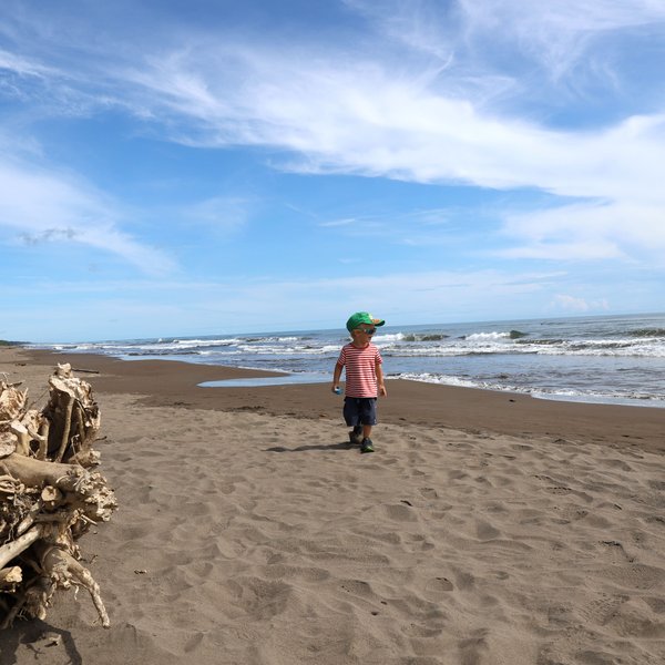 Kind spielt fröhlich am weißen Sandstrand im Tortuguero Nationalpark – Costa Rica Reise mit Kindern