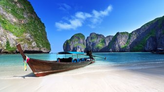 Küstenabschnitt mit Felsformationen und traditionellem Boot – Thailand Reise mit Kindern