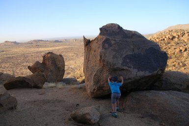 Ein Kind deutet an, einen großen Felsen zu verschieben - Namibia Urlaub mit Kindern