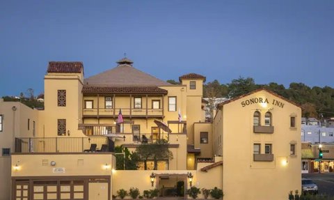 Das Sonora Inn, ein charmantes Hotel, zeigt seine gelbe Fassade und die charakteristische Architektur bei Dämmerung.