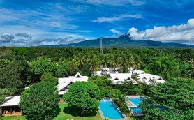 Eine expansive Aussicht auf ein tropisches Resort mit weißen Dächern, Pools und üppigem grünem Garten.