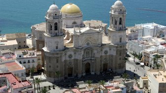 Die beeindruckende Kathedrale von Cádiz mit ihrer goldenen Kuppel erhebt sich majestätisch über das blaue Wasser des Meeres.