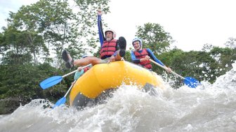 Zwei Männer im Kanu genießen das Wildwasser-Rafting, während sie durch spritzende Wellen paddeln und lachen.
