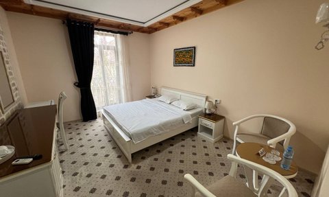 Ein helles Hotelzimmer mit einem großen Bett, einem Tisch und zwei Stühlen, das eine gemütliche Atmosphäre ausstrahlt.
