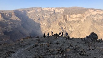 Eine Gruppe von Wanderern steht auf einem felsigen Aussichtspunkt und blickt auf eine beeindruckende Schlucht.