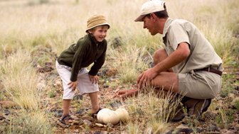 Ein Guide zeigt einem Kind ein Straußenei - Namibia Rundreise mit Kindern