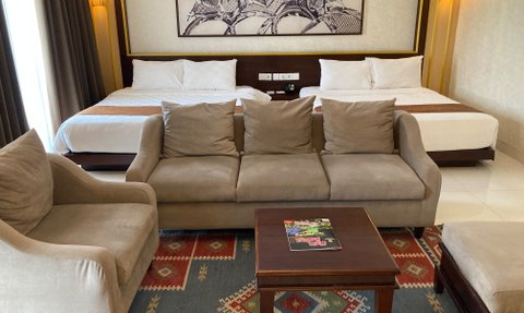 Ein gemütlicher Hotelzimmer mit zwei Betten, einem bequemen Sofa und einem kleinen Tisch auf einem bunten Teppich.