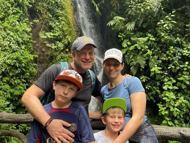 Familie steht vor einem Wasserfall im Nationalpark Arenal – Costa Rica Familienreise