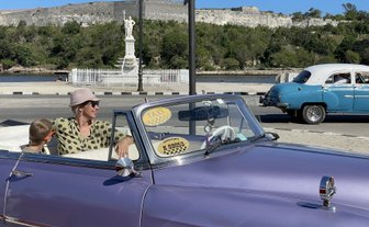 Bunte Oldtimer auf der Straße vor malerischer Kulisse - Kuba mit Kindern