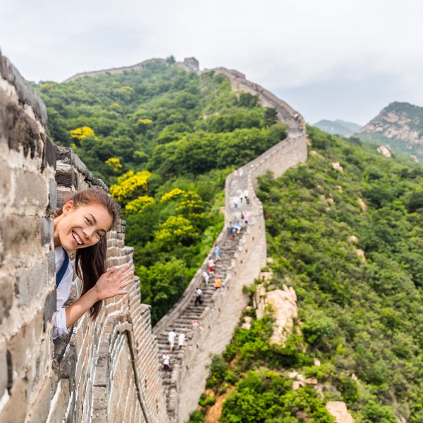 Teenager grüßt von der Großen Mauer mit weitem Blick auf die Landschaft Chinas – China Reise mit Kindern