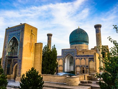 Die beeindruckende Architektur von Samarkand zeigt eine große Kuppel und kunstvoll verzierte Wände unter einem blauen Himmel.
