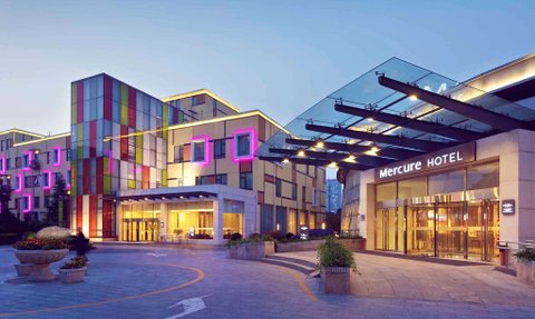 Das Mercure Hotel in Peking zeigt eine moderne Architektur mit bunten Fassaden und stilvollen Lichtern in der Dämmerung.